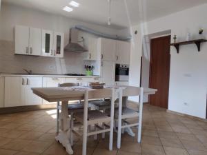 una cucina con armadi bianchi, tavolo e sedie di La Casa Sul Lago a Osiglia