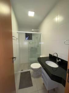 La salle de bains est pourvue d'un lavabo, de toilettes et d'une douche. dans l'établissement Ap no centro piscina e churras, à Ubatuba