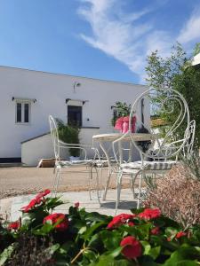 duas cadeiras brancas e uma mesa num jardim em Masseria Santa Maria em Gravina in Puglia