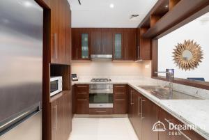 a kitchen with wooden cabinets and a sink at Dream Inn Apartment- Tajer Souk Al Bahar in Dubai