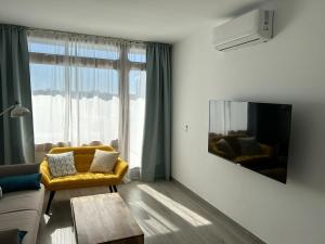 sala de estar con sofá amarillo y ventana grande en Apartamento Jameos-Los Molinos Costa Teguise, Lanzarote, en Costa Teguise