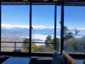 a room with a large window with a view of mountains at Gombo Hideaway in Nagarkot