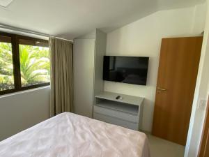 ein Schlafzimmer mit Bett und Flachbildfernseher in der Unterkunft Muro alto Bangalô beach class ecolife in Porto De Galinhas