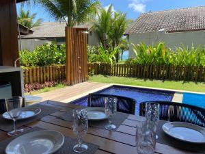 ein Holztisch mit Tellern und Weingläsern darauf in der Unterkunft Muro alto Bangalô beach class ecolife in Porto De Galinhas