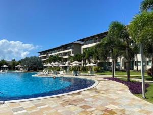 un complejo con una piscina con palmeras y un edificio en Muro alto Bangalô beach class ecolife en Porto De Galinhas