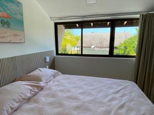 ein Bett in einem Schlafzimmer mit einem großen Fenster in der Unterkunft Muro alto Bangalô beach class ecolife in Porto De Galinhas + 23 Fotos