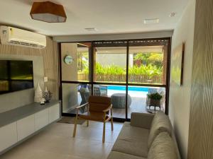 a living room with a couch and a view of a pool at Muro alto Bangalô beach class ecolife in Porto De Galinhas