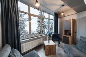 a living room with a couch and a table and windows at BLUE mountain in Bukovel