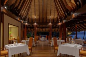 uma sala de jantar com mesas e cadeiras brancas em Anantara Maia Seychelles Villas em Mahé