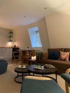 a living room with a couch and tables and a kitchen at The Riding Gate Apartment in Kent
