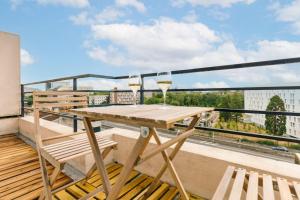 a balcony with a wooden table and two glasses of wine at Marvellous Studio Paris 14 in Gentilly