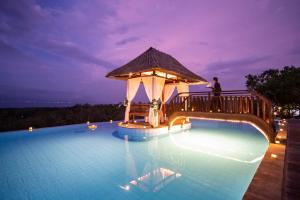 a man standing on a bridge over a swimming pool at night at Semabu Hills Hotel Nusa Penida in Nusa Penida