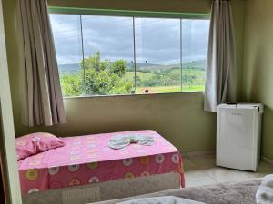 a bedroom with a pink bed and a window at Pousada dos Contos de Carrancas in Carrancas