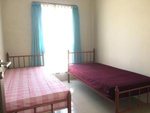 two beds in a room with a window at Dallil Putra Villa in Lembang