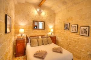 een slaapkamer met een bed in een stenen muur bij Casa Bartolo A Hidden Gem - Spacious Village Home EBAR1-1 in Lija
