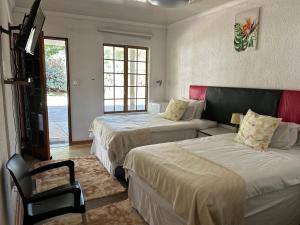 Cette chambre comprend 2 lits et une télévision. dans l'établissement Mihandzu Guest House, à Hazyview