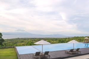 einen Pool mit 2 Sonnenschirmen und Blick auf das Wasser in der Unterkunft Semabu Hills Hotel Nusa Penida in Nusa Penida