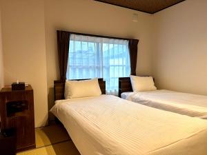 2 camas en una habitación con ventana en 橋旅西雅院 Kyoryosaiga Inn, en Kioto