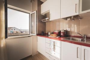 een keuken met witte kasten, een wastafel en een raam bij Best Houses 04 - Loft in the Heart of Peniche in Peniche