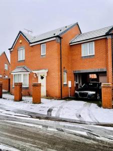 a red brick house with a black car parked in the driveway at Plantsbrook Place - Luxury 4 bed House + Parking in Birmingham