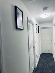 un pasillo con dos puertas blancas y cuadros en la pared en Plantsbrook Place - Luxury 4 bed House + Parking, en Birmingham
