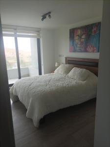 1 dormitorio con 1 cama y una pintura en la pared en Hermoso Departamento dunas de concon, en Concón