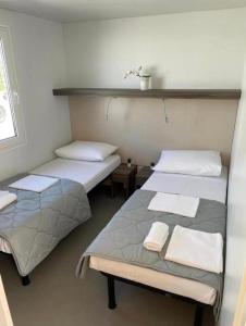 two beds in a small room with towels on them at Mobilna kućica VIA CISSA in Šimuni