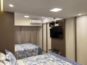 a room with two beds and a flat screen tv at Pipa's Bay - Flats para temporada in Pipa