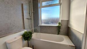 a bathroom with a tub and a toilet and a window at Large 4 bedroom / 7 guests house in Doncaster