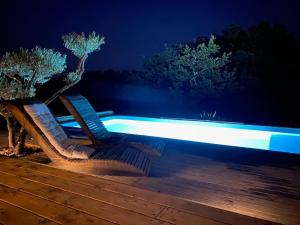 twee stoelen op een terras met een zwembad in de nacht bij Villa Parenthèse in Saint Alban Auriolles