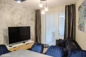 Il comprend un salon doté d'une télévision à écran plat et de chaises bleues. dans l'établissement D Apartments Centrum Prowiantowa, à Białystok