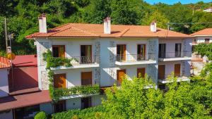 budynek z czerwonymi dachami i drzewami w obiekcie Ξενώνας Μενελαΐς - Menelais Apartments w mieście Thrapsímion