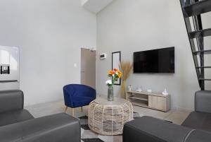 a living room with a couch and a table and a tv at Urban Oasis Apartments at The Bolton in Johannesburg