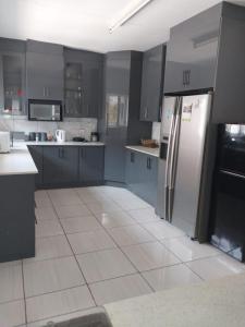 a kitchen with gray cabinets and a stainless steel refrigerator at Vaal holiday home in Vanderbijlpark