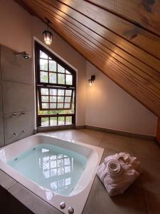 a large bath tub in a bathroom with a window at Capivari Lodge vista incrível da natureza in Campos do Jordão