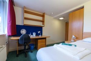 a hotel room with a desk and a bed at Beit Hall in London
