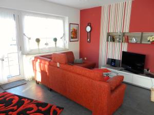 グレートジールにあるFerienwohnung Sonnenkieker Greetsielのリビングルーム(オレンジ色のソファ、テレビ付) +9枚の写真