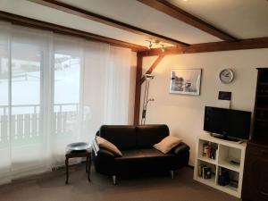 ein Wohnzimmer mit einem Stuhl und einem TV in der Unterkunft Chli Alpa B13 in Arosa