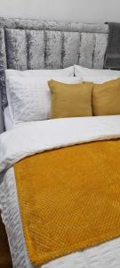 een bed met gele en witte lakens en kussens bij 1 bed studio in Luton
