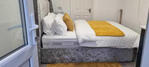 a bedroom with a bed with white and gold pillows at 1 bed studio in Luton