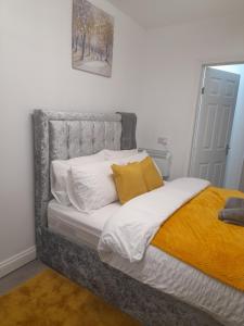 een bed met witte en gele kussens in een slaapkamer bij 1 bed studio in Luton