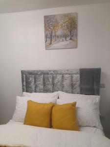 a bed with yellow pillows and a painting above it at 1 bed studio in Luton