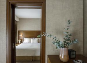 ein Schlafzimmer mit einem Bett und einer Vase mit einer Pflanze in der Unterkunft Anatolia Hotel in Thessaloniki