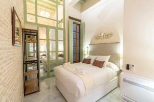 Un dormitorio con una gran cama blanca y una ventana en Judería de Sevilla I Luxury Apartments, en Sevilla