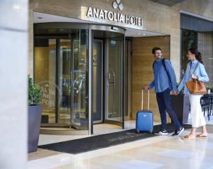 Ein Mann und eine Frau mit einem Koffer vor einem Hotel. in der Unterkunft Anatolia Hotel in Thessaloniki