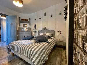 Schlafzimmer mit einem Bett mit gestreifter Decke in der Unterkunft Maison de l'Horloge in Riorges