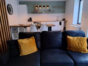 ein Wohnzimmer mit einem blauen Sofa und gelben Kissen in der Unterkunft Gîte Chez Nénene La Roche en Ardenne in La-Roche-en-Ardenne