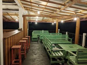 a room with green wooden benches and a bar at Cozy Crest in Ahangama