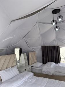 a bedroom with two beds and a desk in a tent at Blue Dome Chalet شاليه القبة الزرقاء in Al Raka