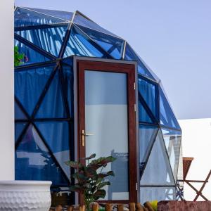 una casa in vetro blu con porta in legno di Blue Dome Chalet شاليه القبة الزرقاء a Al Raka